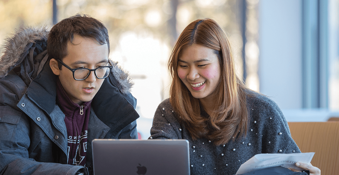 Two students working on a laptop